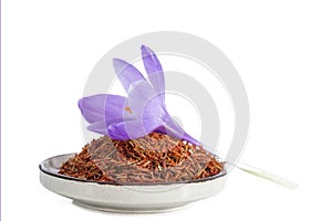 Flower crocus and dried saffron spice in a bowl on white background.