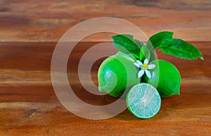 Flower, cut and whole limes on wooden background
