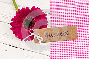 Flower with gift tag with german word, Auszeit, means relax