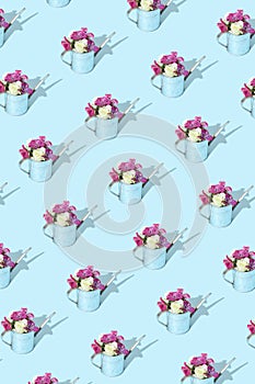 Flower inside metal watering can on pastel blue background. Minimal creative garden pattern with sunshine and hard shadow. Summer