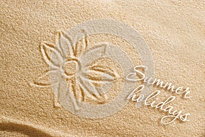 The flower is painted on the sand and the inscription is summer holidays. Beach background. View from above. The concept of summer