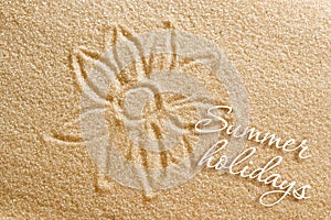 The flower is painted on the sand and the inscription is summer holidays. Beach background. View from above. The concept of summer