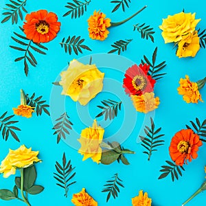 Flower pattern of yellow and red flowers with leaves on blue background. Flat lay, top view. Floral background.
