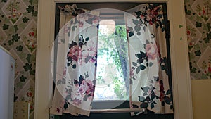 Flower-patterned wall and curtain with bright window in kitchen