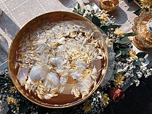 Flower petals in Thai-styled golden bowl filled with water for Songkran festival