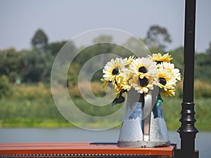 Flower pot shaped watering can and yellow plants placed by the river