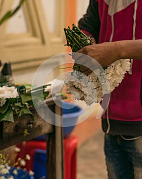 A flower seller is binding dahlia flower for making flower bouquet