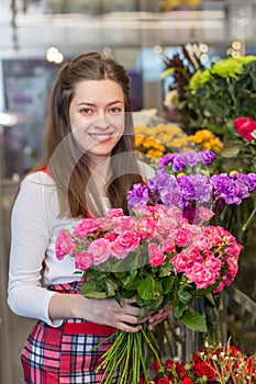 Flower seller, young woman standing at shop with flower in hands