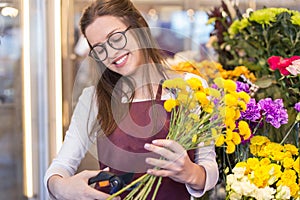 Flower seller, young woman standing at shop with flower in hands