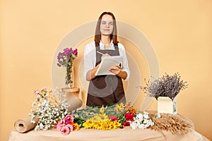 Flower shop ambiance. Workplace floral arrangements. Skilled floral designers at work. Florist woman with clipboard writing and