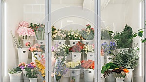 Flower shop concept. Different varieties fresh spring flowers in refrigerator room for flowers. Bouquets on shelf