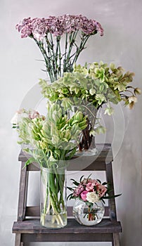 Flower shop concept. Different varieties fresh spring flowers on wooden chair table. Bouquets on shelf, florist business.