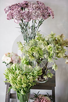 Flower shop concept. Different varieties fresh spring flowers on wooden chair table. Bouquets on shelf, florist business.