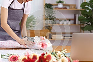 Flower shop concept, Female florist wrapping and creating colorful flowers bouquet with paper