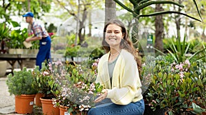 In flower shop, girl chooses flowering rhaphiolepis plant for outdoor garden decor photo