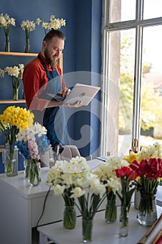 Flower shop owner concept. Florist businessman working in flower shop using laptop computer