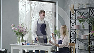 Flower shop, young specialist girl together with employee takes an order to deliver bouquet of flowers by phone and