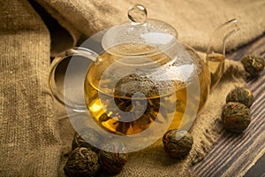 Flower tea brewed in a glass teapot on a background of homespun fabric with a rough texture. Close up