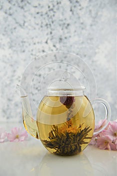 Flower tea in glass teapot on white