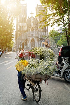 Flower vendor on Hanoi street at early morning with St. Joseph Cathedral church on background