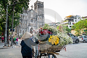 Flower vendor on Hanoi street at early morning with St. Joseph Cathedral church on background