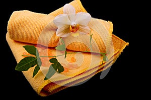 Flower yellow-orange orchids and orange towel on glossy black ba