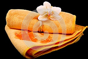 Flower yellow-orange orchids and orange towel on glossy black ba