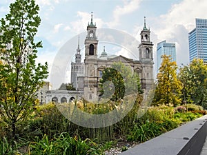 Flowerbed with green autumn plants in the background of All Saints Church and PKiN in Warsaw, Poland. Cityscape of the Polish photo