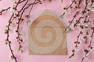 Flowering branch. Spring flowers and craft envelopes on a bright pink background. top view