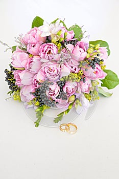 Bouquet of purple peonies and blueberries alongside two wedding rings. Paeoniaceae. photo