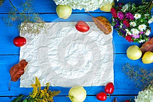 Flowers,apples,plums and sheet of paper on a blue table