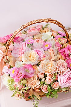 Flowers arrangement with various of colors in wicker basket on pink table. beautiful spring bouquet. bright room, white