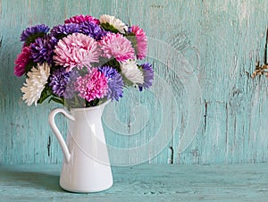 Flowers asters in white enameled pitcher