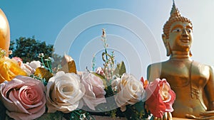 Flowers on a background of a large golden Buddha in the temple of Thailand. Pattaya