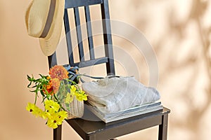 flowers in basket, clothes and hat on old chair