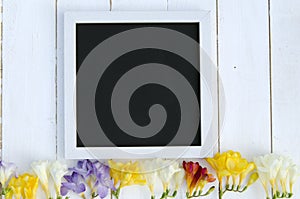 Flowers with blank black chalkboard picture frame on a light wooden background. romantic picture.