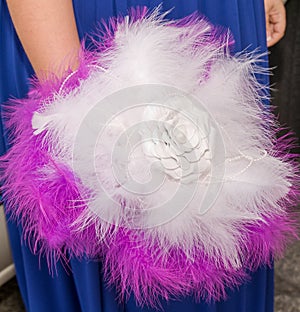 Soft bouquet in the hand of a bride made with white and purple feathers with a fabric flower in the center photo