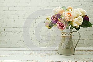 Flowers Bouquet in metal vase home decor on white brick wall and wooden background