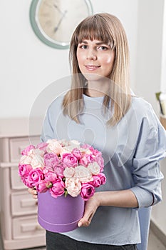 Flowers bouquet in violet headbox. Young happy woman holding a beautiful bunch of pink roses. Present for a smiles girl