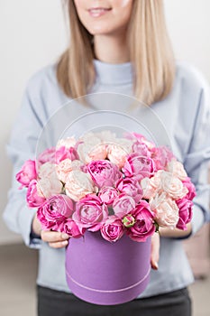 Flowers bouquet in violet headbox. Young happy woman holding a beautiful bunch of pink roses. Present for a smiles girl