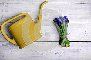 Flowers bouquet with watering can on wooden table. Top view