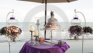 Flowers bouquets and wedding cake on a table on a beach during a traditional Thai wedding