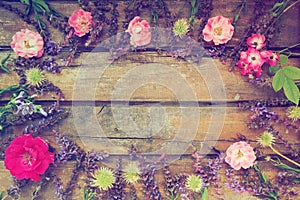 Flowers in a circle on a wooden background. Postcard for the holiday. Roses, geraniums, lavender, sage and hairy