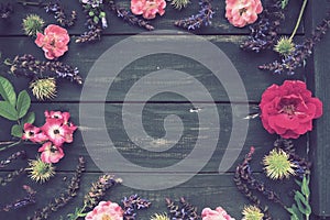 Flowers in a circle on a wooden background. Postcard for the holiday. Roses, geraniums, lavender, sage and hairy