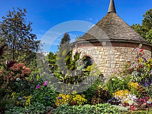 Flowers by circular stone building in botanical garden