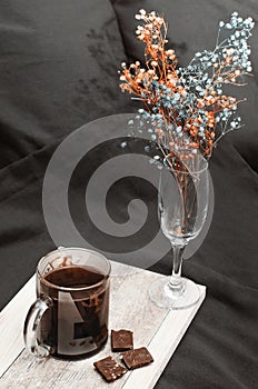Flowers and coffee with chocolate in bed at home. Cozy home interior, black linens. Vertical photography