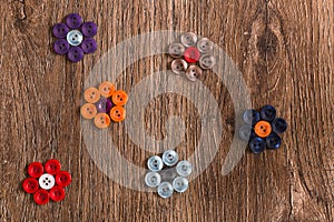 Flowers of colorful sewing buttons on a wooden background