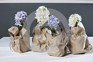 The Flowers composition with lilac and white hyacinths wrapped in kraft paper . Spring flowers on white background. Easter concept