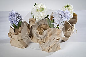The Flowers composition with lilac and white hyacinths wrapped in kraft paper . Spring flowers on white background. Easter concept