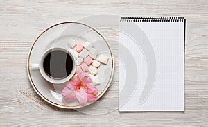 Flowers composition. Notebook and cup of coffee with pink flowers and leaves. Top view, flat lay, place for text